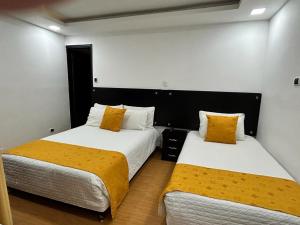 2 bedden in een kamer met witte en gele kussens bij Hostal Habitaciones de la 39 in Pasto