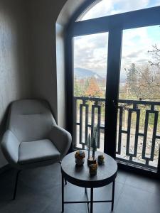 sala de estar con silla, mesa y ventana en ApartHotel, en Mukácheve