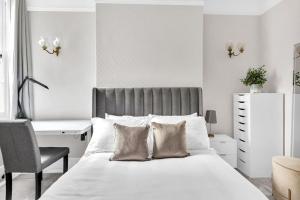 a bedroom with a bed with a desk and a chair at Luxury 3 bedroom apartment in the heart of High Street Kensington, London. in London