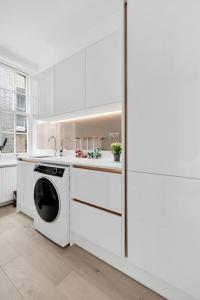 a white kitchen with a dishwasher and a sink at Luxury 3 bedroom apartment in the heart of High Street Kensington, London. in London