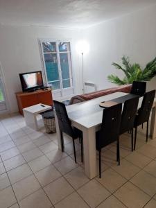 a dining room with a table and chairs and a television at maison agréable pour 6 a 5 mm de Disney in Magny-le-Hongre