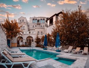 a pool with chairs and umbrellas in front of a building at Tekkaya Cave Hotel in Göreme