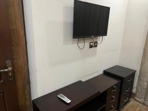 a tv on a wall with a table and a remote control at Prime Plaza in Gujrānwāla