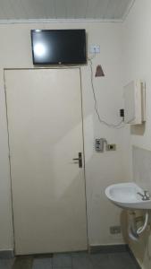 a bathroom with a sink and a tv on the wall at Hotel Vitoria Andradina in Andradina