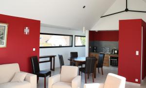 a dining room with red walls and a table and chairs at Gîtes " Arromanches" ou "Bord de Mer PMR" 2 chambres en FRONT DE MER à Asnelles , 3km d'Arromanches, 10km de Bayeux in Asnelles