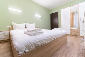 a bedroom with a large white bed with towels on it at City Central 1-Bed Apartments in Plovdiv