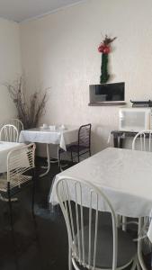 a restaurant with white tables and chairs and a vase of flowers at Hotel Vitoria Andradina in Andradina