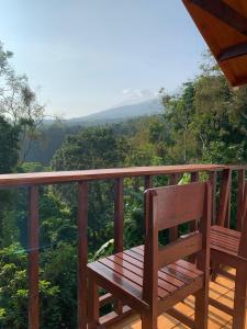 eine Holzbank auf einem Balkon mit Aussicht in der Unterkunft Poetri Bungalow & Restaurant in Senaru