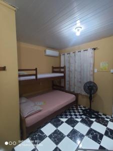 um quarto com 2 beliches e um piso em xadrez em Morada das Flores Chalé/Kitnet na Ilha do Mel