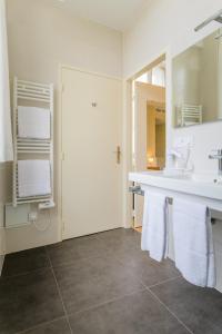 a bathroom with a sink and a mirror and towels at Hôtel Grand Monarque in Azay-le-Rideau