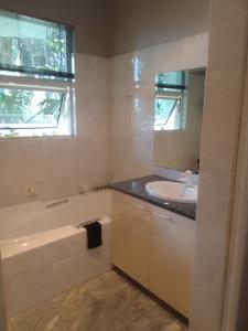 a bathroom with a sink and a bath tub and a mirror at Blue Oasis Apartments in Benoni