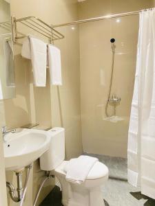 a bathroom with a toilet and a sink and a shower at Ruma Ruma Hotel Kenten - Palembang in Sukarami