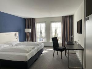 アーレンにあるDas Goldene Lamm Aalenのベッド、デスク、椅子が備わるホテルルームです。