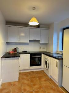 a kitchen with white cabinets and a dishwasher at City Pulse Apartment in Waterford