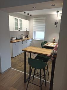 een keuken met een houten tafel en groene stoelen bij Dream House in Vršac