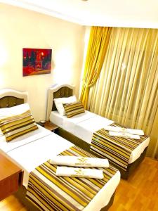two beds in a hotel room with yellow curtains at MARDİA CİTY OTEL in Istanbul
