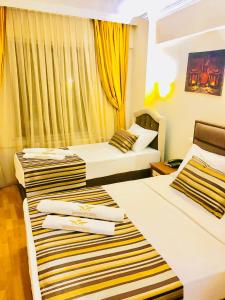 2 bedden in een hotelkamer met gele gordijnen bij MARDİA CİTY OTEL in Istanbul