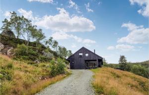 a black barn on a hill with a dirt road at Gorgeous Home In Jsenfjorden With Sauna in Gullingen