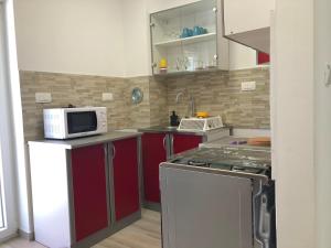 a kitchen with red cabinets and a microwave at Apartmani Hržan-Keglević in Mandre +4 photos
