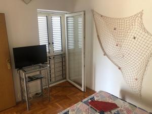 a bedroom with a bed and a tv and a window at Apartmani Hržan-Keglević in Mandre