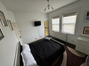 een slaapkamer met een bed en een televisie. bij Luxury Cottage Room in Londen