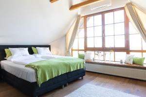 a bedroom with a bed with a green blanket and two windows at Sattlerhof Genießerhotel & Weingut in Gamlitz