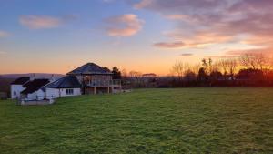 a house in a field with the sunset in the background at 18th century renovated barn in beautiful Devon countryside in Broadwoodwidger