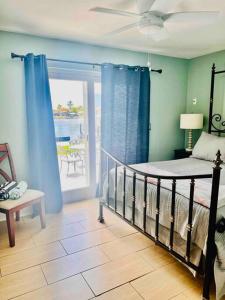 a bedroom with a bed with blue curtains and a patio at Cozy 2 bedrooms home by the water in Cape Coral