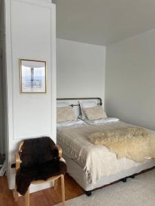 a white bedroom with a bed and a chair at Top floor apt with stunning view 