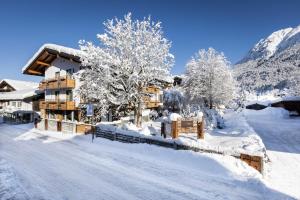 a house covered in snow with trees and mountains at Casatina Ferienwohnungen in Oberstdorf