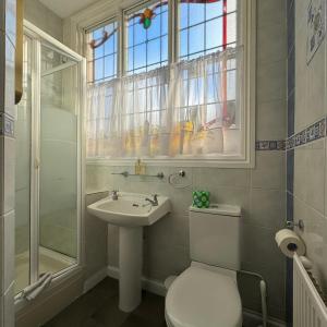a bathroom with a toilet and a sink and a window at Fairlawns Guest House in Banbury