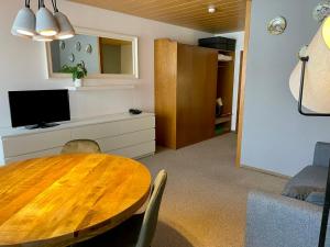 a dining room with a wooden table and a television at Kleinwalsertal Apartment in Mittelberg