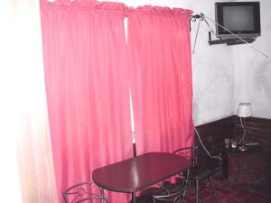 - une table et des chaises dans une chambre dotée de rideaux roses dans l'établissement La Pastora, à Punta del Este