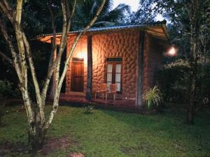 a small log cabin with a porch at night at River Cottage Safari in Udawalawe