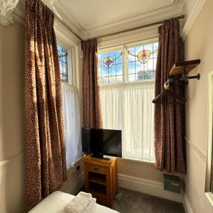 um quarto com uma cama, uma televisão e uma janela em Fairlawns Guest House em Banbury