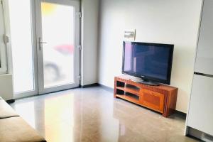 a living room with a flat screen tv on a wooden stand at Bliss Apartments T0 - Maria (On the beach) in Mindelo