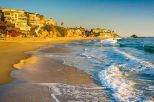 a beach with buildings and the ocean and waves at Hello Sunshine OC minutes to Disneyland-Family Friendly in Fullerton