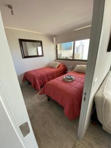 2 camas en una habitación con mantas rojas en Hermoso y comodo Departamento con vista al mar, costas de montemar, en Concón