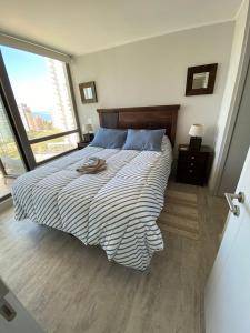 una camera da letto con un grande letto con un piumone a righe di Hermoso y comodo Departamento con vista al mar, costas de montemar a Concón