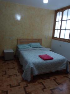 Un dormitorio con una cama con una toalla roja. en Departamento luxor en Cajamarca