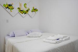 um quarto com uma cama branca e toalhas em Apartamento na praia - Canto da Sereia em Piçarras