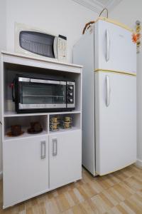 eine weiße Küche mit einer Mikrowelle und einem Kühlschrank in der Unterkunft Apartamento na praia - Canto da Sereia in Piçarras