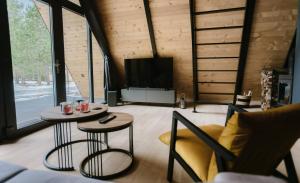 uma sala de estar com duas mesas e uma televisão em Pinery Blidinje A-Frame House em Blidinje