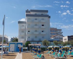 un edificio con sedie e ombrelloni di fronte di Hotel Driade sul mare a Rimini