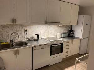 a kitchen with white cabinets and a sink and a refrigerator at Leilighet i Hagavik 