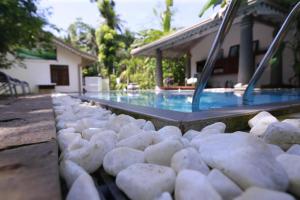 un montón de rocas blancas sentadas junto a una piscina en Villa Lotus en Hikkaduwa