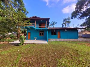 a blue house with a yard in front of it at Suítes Barra da Lagoa in Ubatuba
