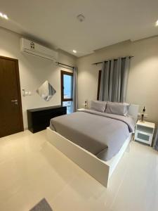 a white bedroom with a large bed and a window at The Beach House deux in Muscat