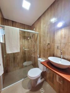 a bathroom with a toilet and a sink and a shower at Suítes Barra da Lagoa in Ubatuba