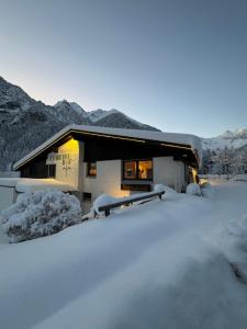 una casa cubierta de nieve con montañas en el fondo en Brandnerhof, en Brand